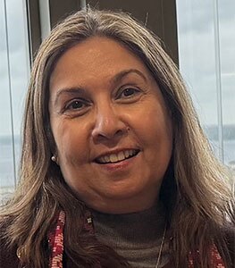 Headshot of Dr. Ayesha Mirza, smiling, with long light brown hair, in an office setting