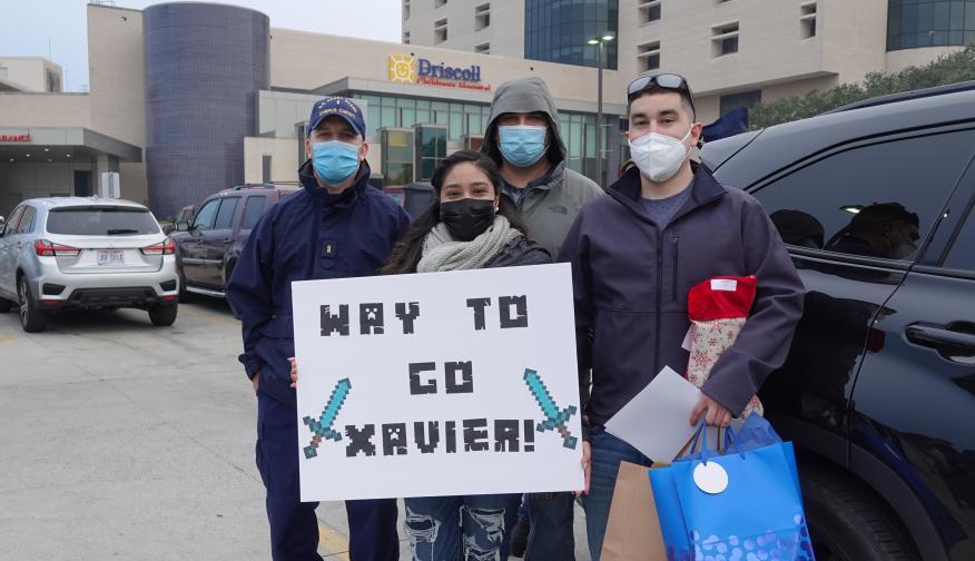 Wait to go Xavier, a family holds a sign in front of the hospital.