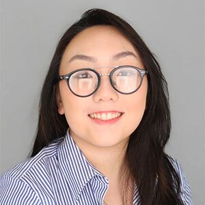 Smiling young woman with glasses and long dark hair wearing a red button up collard shirt.
