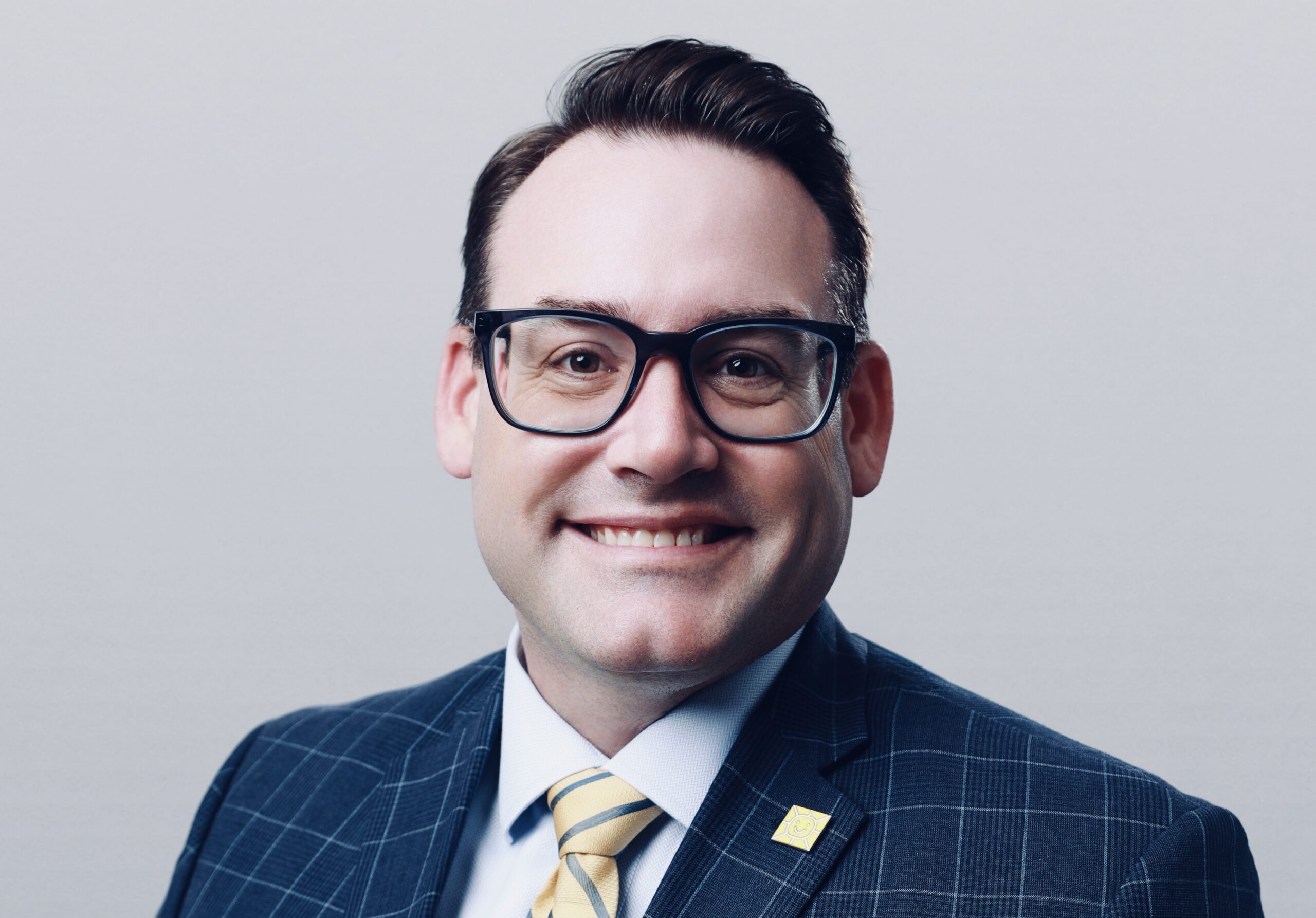 Professional headshot of Jason Geiken wearing glasses and a suit and tie.
