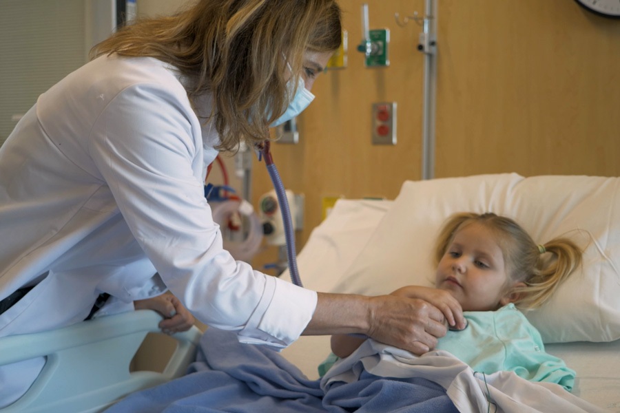 A female doctor listen's to a young girl's heart with a stethoscope.