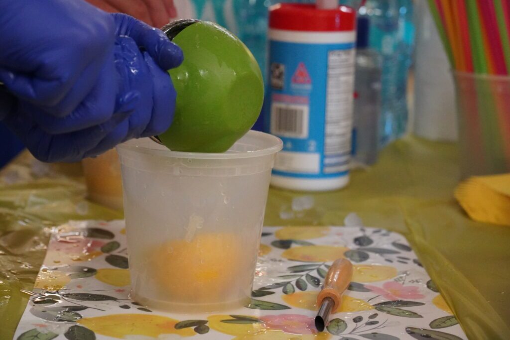 Closeup on a hand squeezing fresh lemon juice in a plastic pint container.