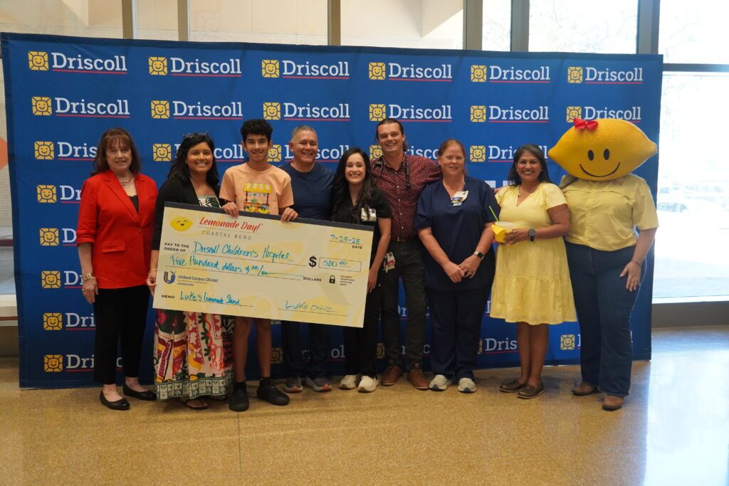 Luke holding a large $500 check he is donating to the hospital.