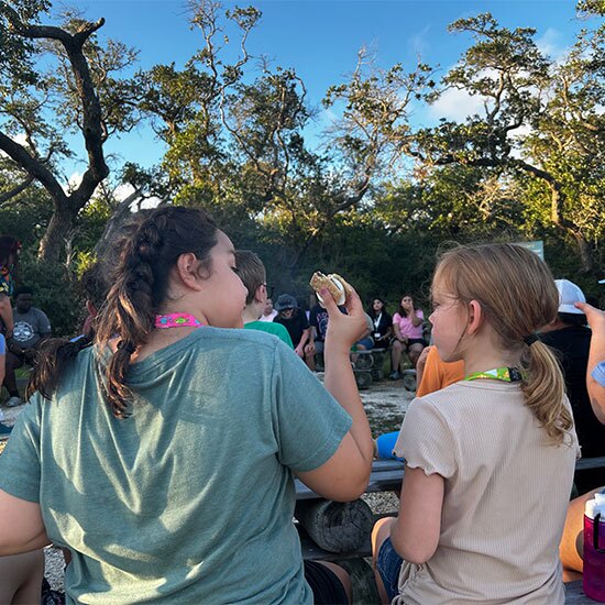 Two girls eating lunch together at camp.