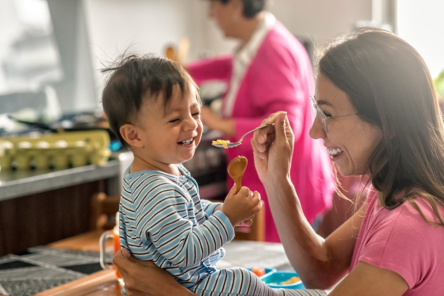 Mother spoon feeding her happy baby.