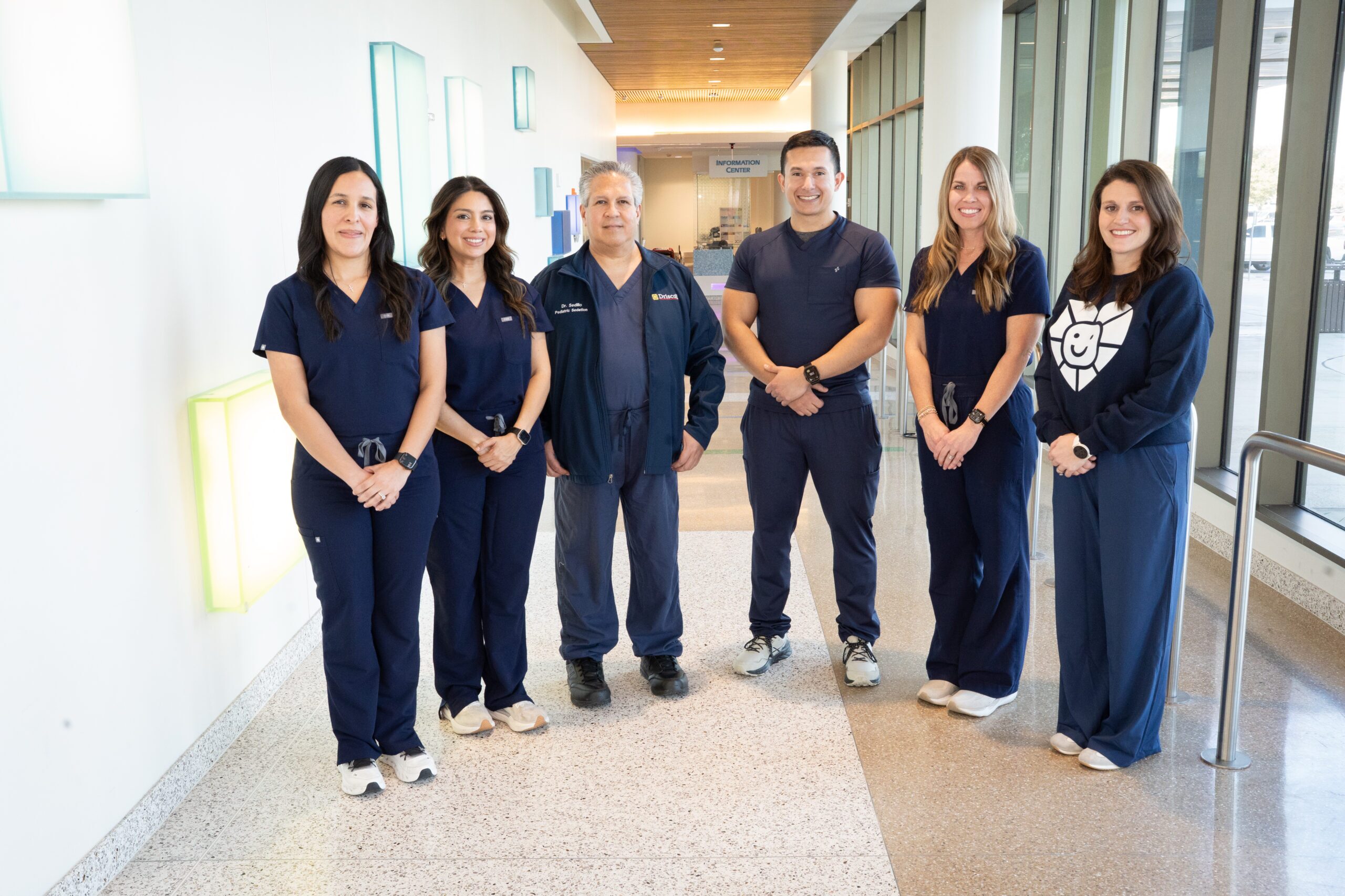 The pediatric sedation team of six is standing together in a hallway at Driscoll Children's Hospital.