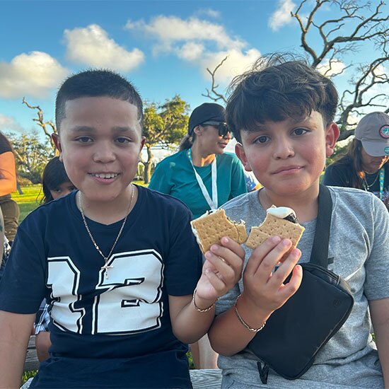 Two smiling boy eating smores at camp.