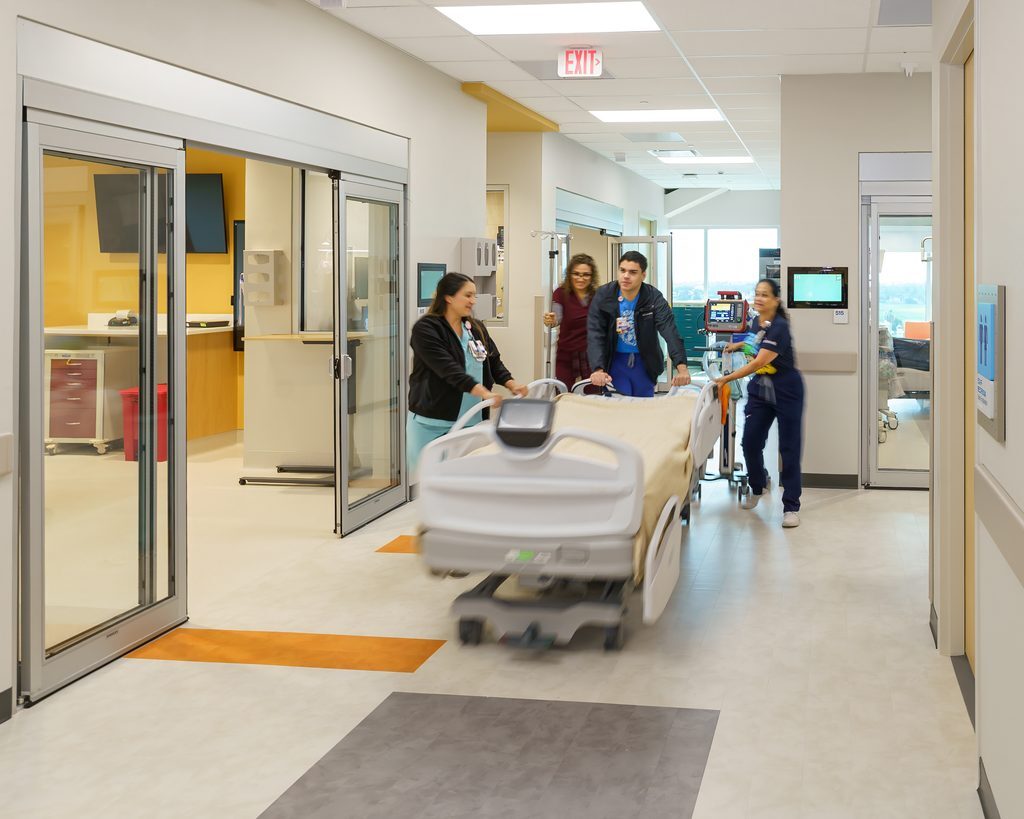 clinical staff push bed inside PICU