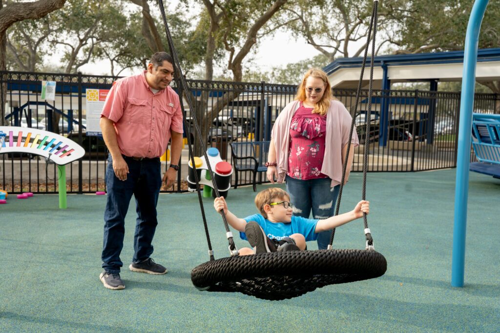 man and woman, mother and father, watch son swing