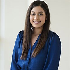 Headshot of Larisa Garcia, smiling, with long dark hair, wearing a blue blouse.